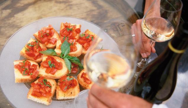 Un piatto con Bruschette e due calici di vino bianco
